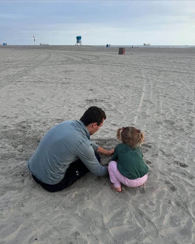 Erika's daughter is playing in sand with her father.